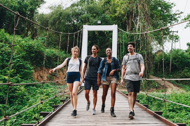 Gruppo di amici che camminano sul ponte in un&#39;avventura di campagna tropicale