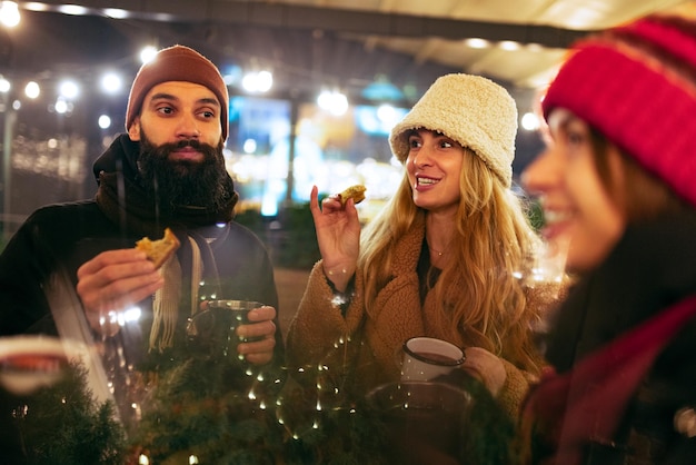 Gruppo di amici che celebrano le vacanze fuori, bevono vin brulé, si divertono. Vacanze invernali