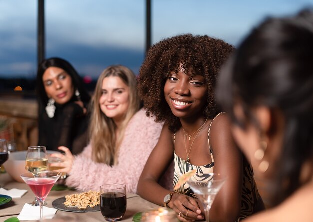 Gruppo di amici che cenano allegramente al tramonto su una terrazza