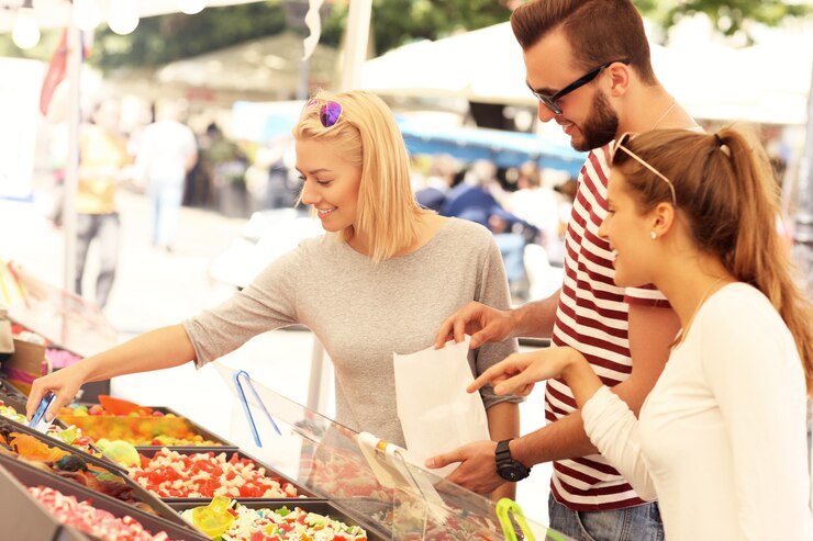 gruppo di amici che comprano caramelle gommose al mercato