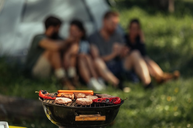 Gruppo di amici che fanno barbecue durante il campeggio nei boschi