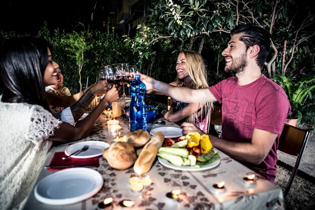 Gruppo di amici che fanno barbecue nel cortile all'ora di cena