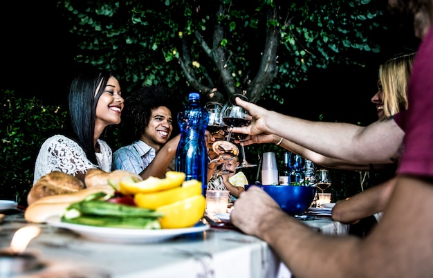 Gruppo di amici che fanno barbecue nel cortile all'ora di cena