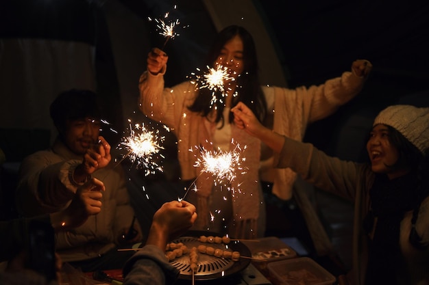 Gruppo di amici che festeggiano insieme con scintillanti fuochi d'artificio la sera