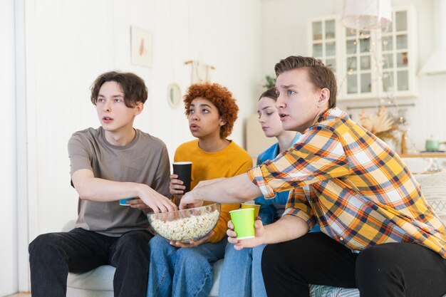 Gruppo di amici che guardano una partita di calcio in TV, tifosi felici che festeggiano