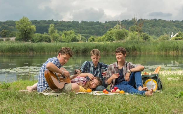 Gruppo di amici che hanno un picnic vicino al fiume