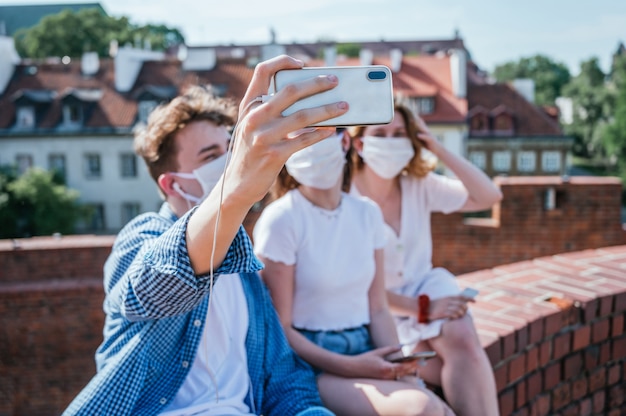 Gruppo di amici che indossano la maschera per il viso e fanno un selfie