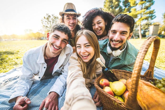 Gruppo di amici che scattano foto ritratto selfie con lo smartphone sul prato di erba