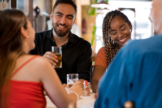 Gruppo di amici che si divertono a bere un bicchiere di birra insieme in un bar o in un pub. Concetto di amici.