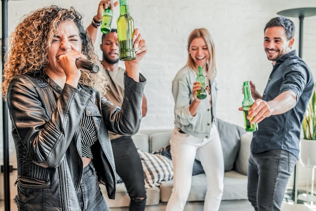 Gruppo di amici che si divertono insieme mentre giocano al karaoke a casa. Concetto di amici.