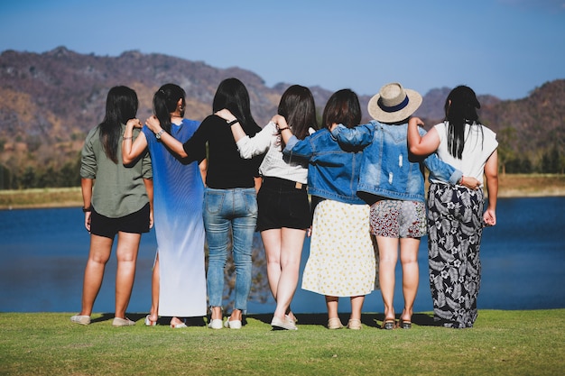 Gruppo di amici che si siedono felicemente insieme vicino al lago