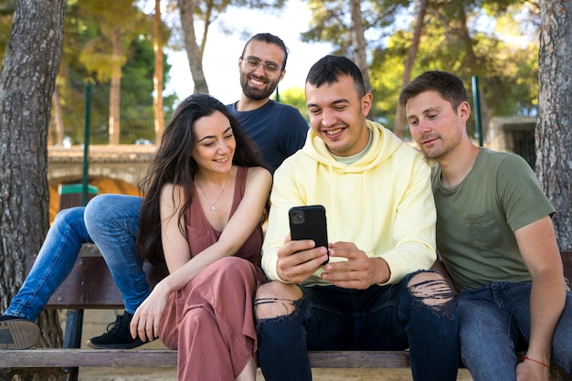 Gruppo di amici che sorridono e guardano i loro telefoni cellulari