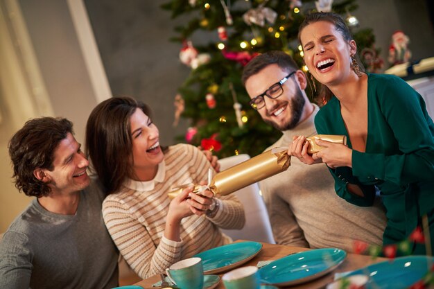 gruppo di amici che tirano i cracker di Natale a casa