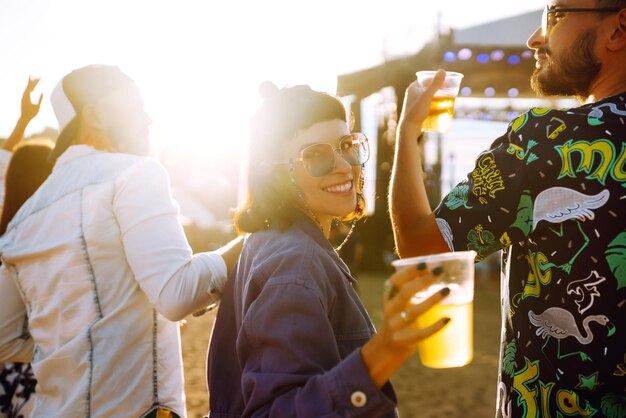 Gruppo di amici con birra che ballano e si divertono insieme al festival musicale Summer Beach party