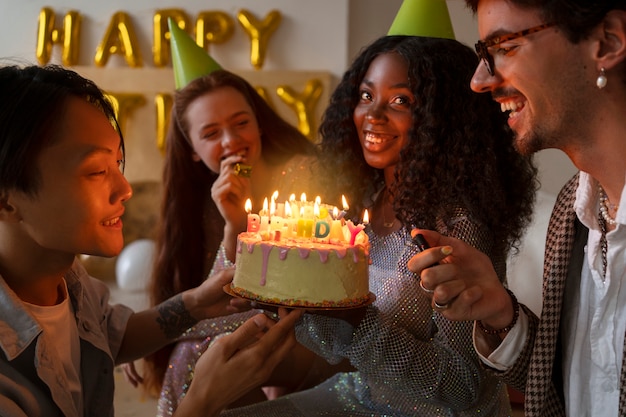 Gruppo di amici con la torta a una festa di compleanno a sorpresa