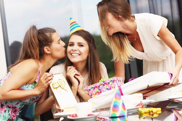 Gruppo di amici con torta e regali che festeggiano il compleanno