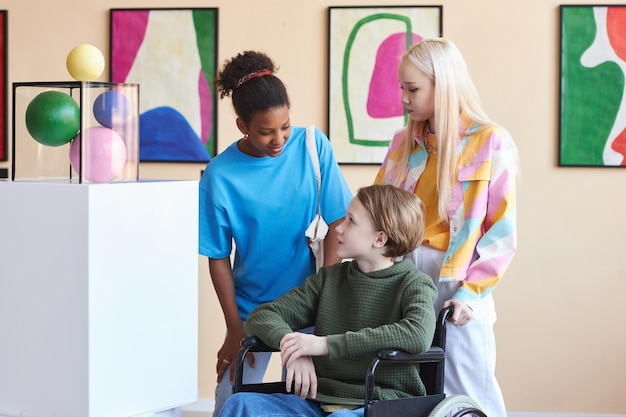 Gruppo di amici con un adolescente in sedia a rotelle che visita la galleria d'arte