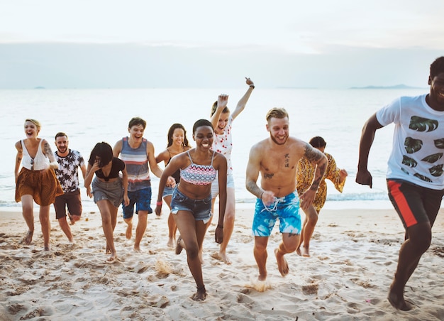 Gruppo di amici diversi che corrono insieme in spiaggia