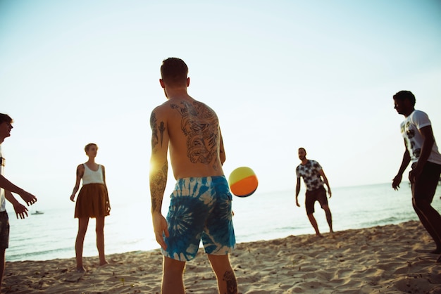 Gruppo di amici diversi che giocano insieme il beach ball