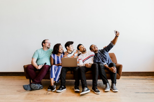 Gruppo di amici diversi che si fanno un selfie su un divano