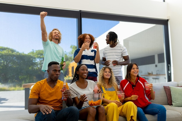 Gruppo di amici diversi seduti sul divano, guardando lo sport in tv e facendo il tifo