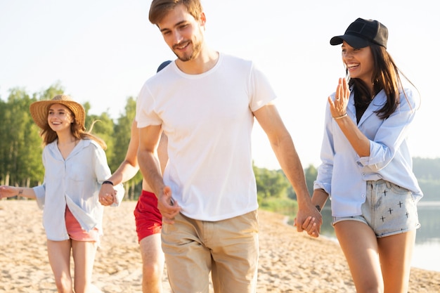 Gruppo di amici divertendosi correndo lungo la spiaggia