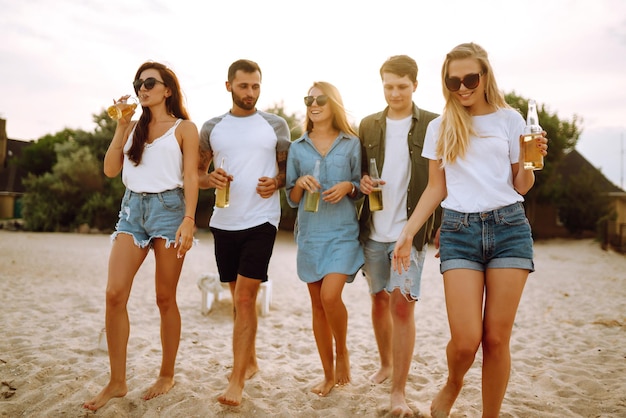 Gruppo di amici esulta e beve birra sulla spiaggia Giovane amico che si rilassa e fa un picnic Summertime