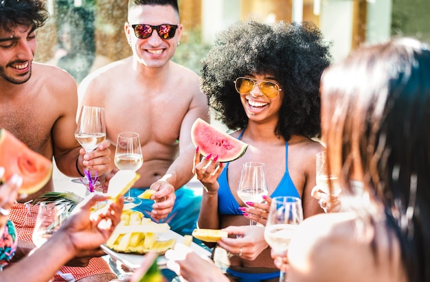 Gruppo di amici felici che bevono champagne con vino bianco alla festa a bordo piscina