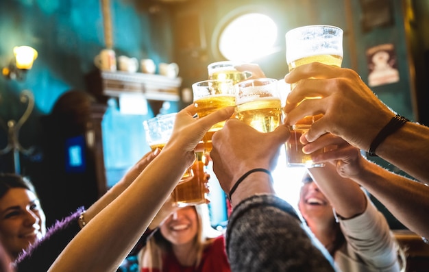 Gruppo di amici felici che bevono e tostano birra al bar