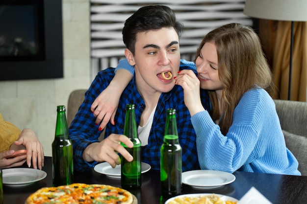 Gruppo di amici felici che bevono mangiando pizza e hamburger al bar ristorante