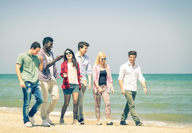 Gruppo di amici felici che camminano a parlare in spiaggia