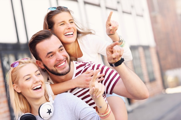 gruppo di amici felici che sorridono alla telecamera e puntano allo spazio della copia