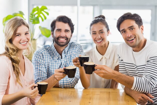 Gruppo di amici felici che tengono tazza di caffè