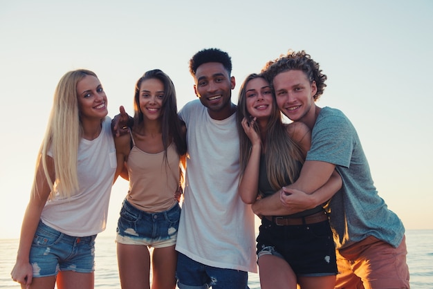 Gruppo di amici felici divertendosi alla spiaggia dell'oceano all'alba