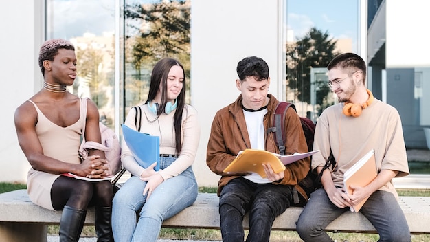 Gruppo di amici seduti in fila fuori dall'università a discutere di appunti di classe