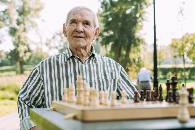 Gruppo di amici senior che giocano a scacchi al parco. Concetti di stile di vita su anzianità e terza età