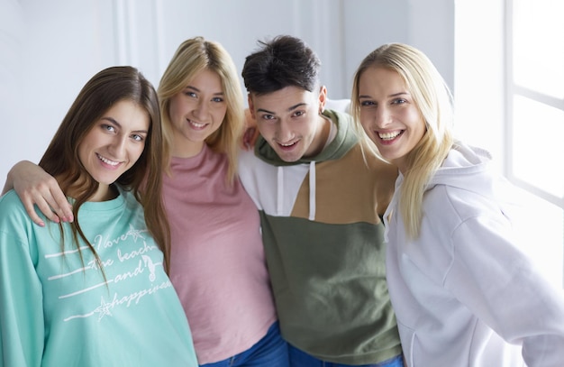 Gruppo di amici sorridenti felici di giovani in piedi e abbracciati insieme