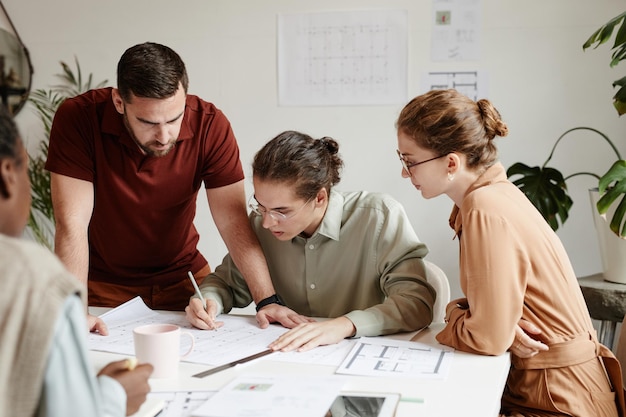 Gruppo di architetti creativi che discutono del progetto della planimetria durante la riunione del team