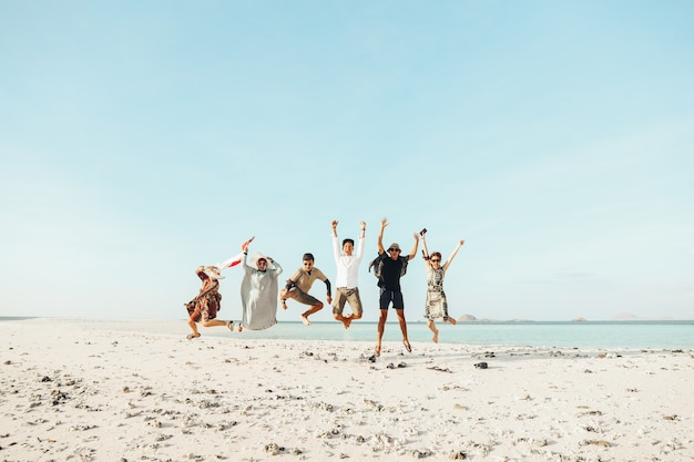 Gruppo di asiatici entusiasti che si godono le vacanze saltando insieme sulla spiaggia