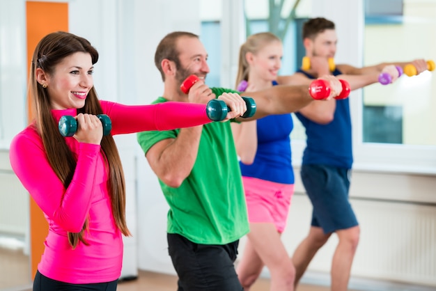 Gruppo di atleti in palestra facendo ginnastica con manubri