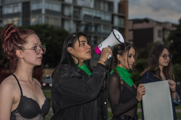 Gruppo di attiviste femministe che tengono cartello con slogan femministi e altoparlante megafono in strada