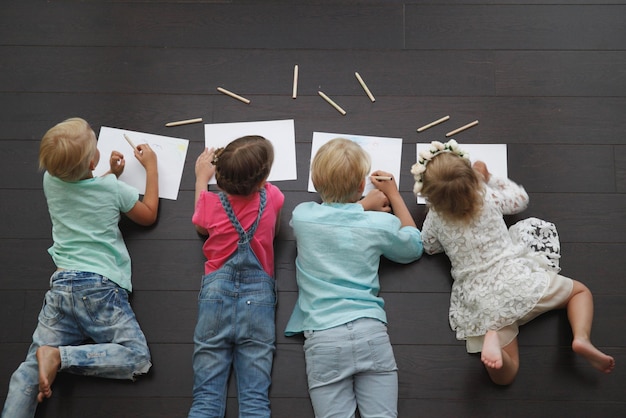 Gruppo di bambini carini che disegnano con matite colorate sul pavimento