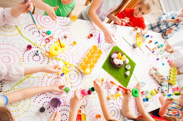 Gruppo di bambini che dipingono le uova di Pasqua Amici sulla festa di Pasqua insieme, amicizia