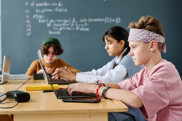 Gruppo di bambini che lo studiano usando i computer seduti in classe