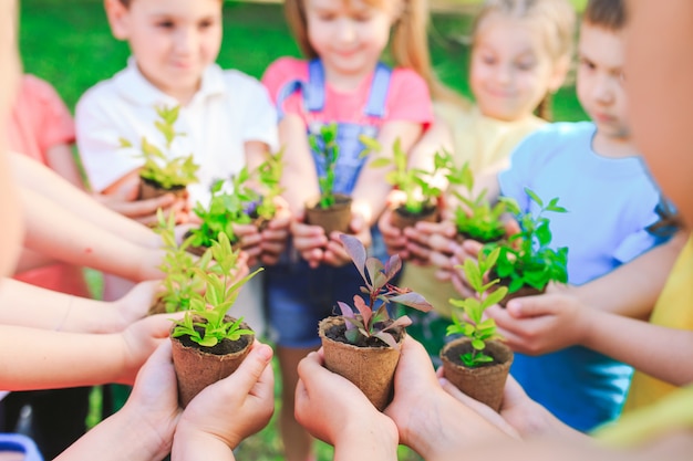 gruppo di bambini che tengono le piante in vasi di fiori