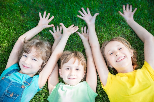 gruppo di bambini felici che giocano all'aperto bambini che si divertono nel parco di primavera amici sdraiati sull'erba