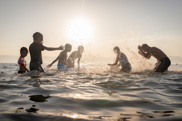 Gruppo di bambini felici che giocano e schizzi nella spiaggia del mare.