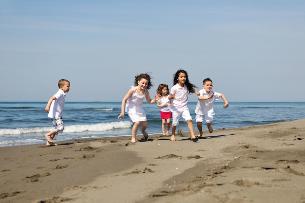 gruppo di bambini felici sulla spiaggia che si divertono e giocano