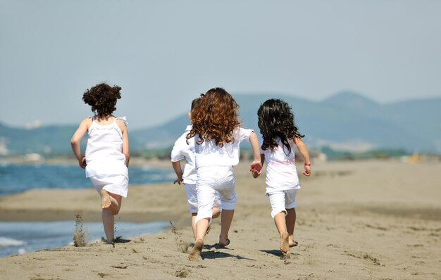 gruppo di bambini felici sulla spiaggia che si divertono e giocano