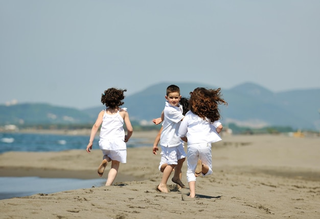 gruppo di bambini felici sulla spiaggia che si divertono e giocano